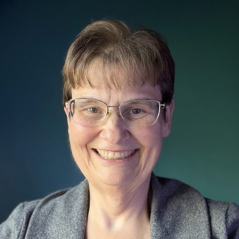 Kelli Marcus, smiling, in a gray cardigan